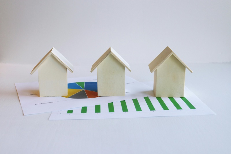 Wooden model houses on graphs depict real estate market analysis and trends.