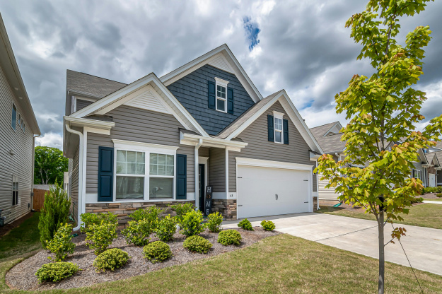A beautiful suburban house with a manicured garden and cloudy sky, exemplifying modern architecture.