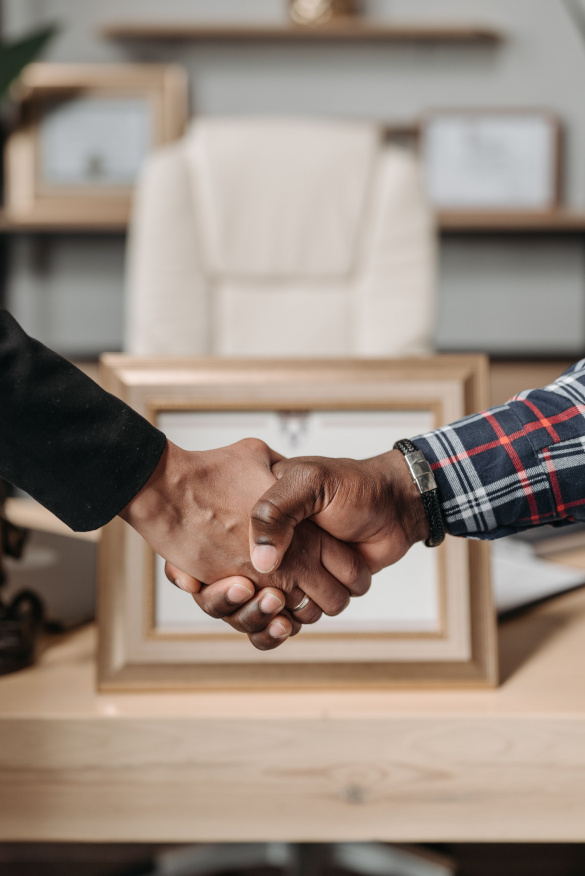 Close-up of a handshake between two individuals in a professional office setting.